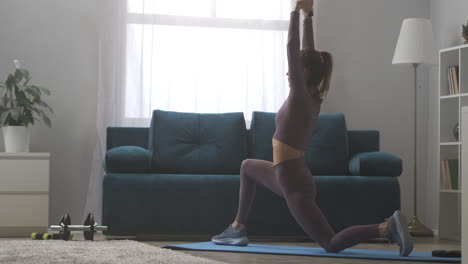 Gymnastik-Zum-Dehnen-Zu-Hause-Frau-Führt-Yoga-Asana-Kriegerpose-Zum-Dehnen-Der-Muskeln-Aus-Und-Trainiert-Allein-Im-Wohnzimmer
